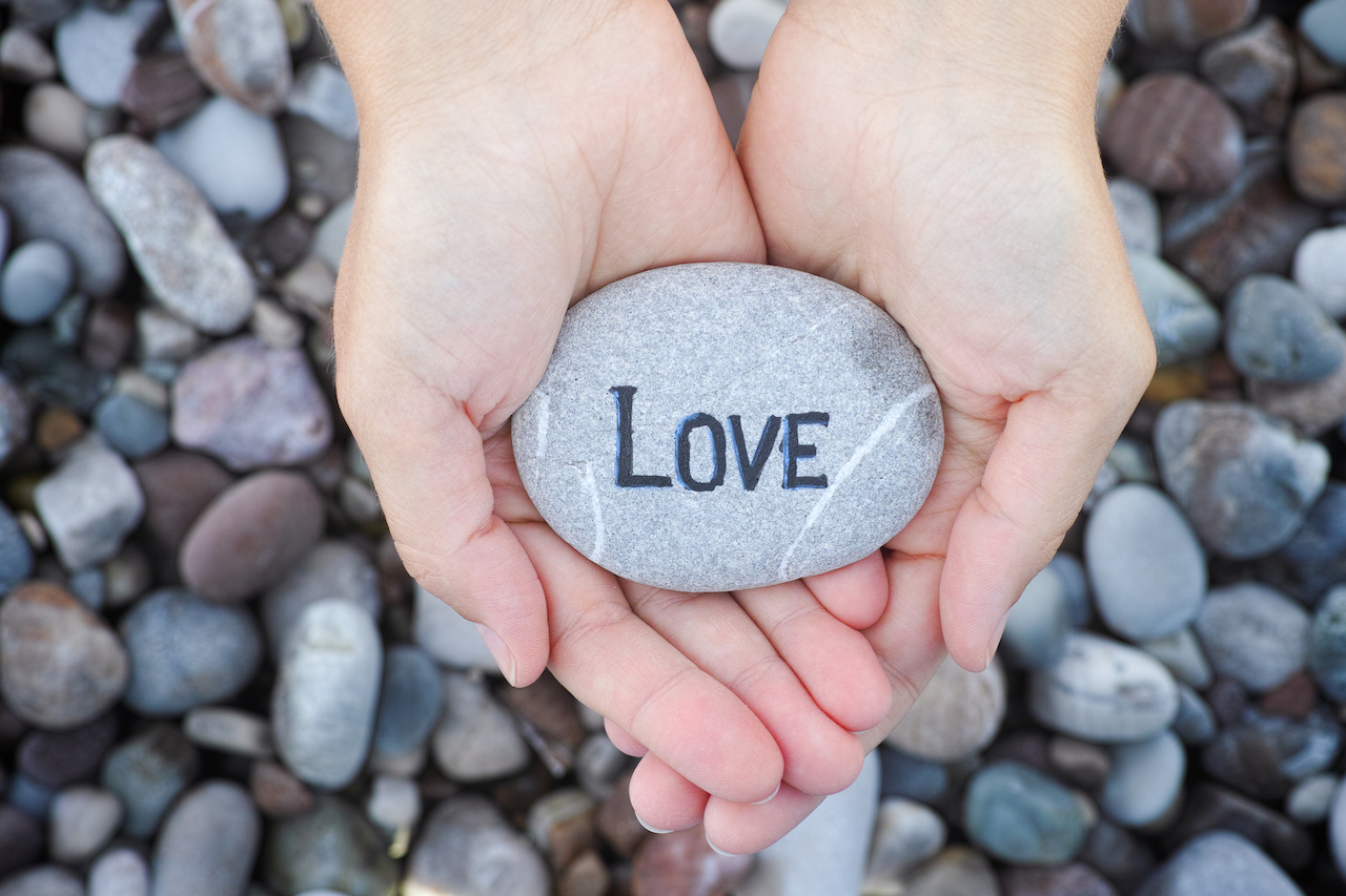 Woman holding stone with the word Love in her palms