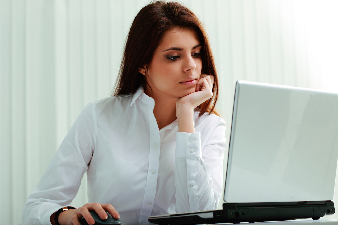Young businesswoman in headphones working on a laptop at office ...