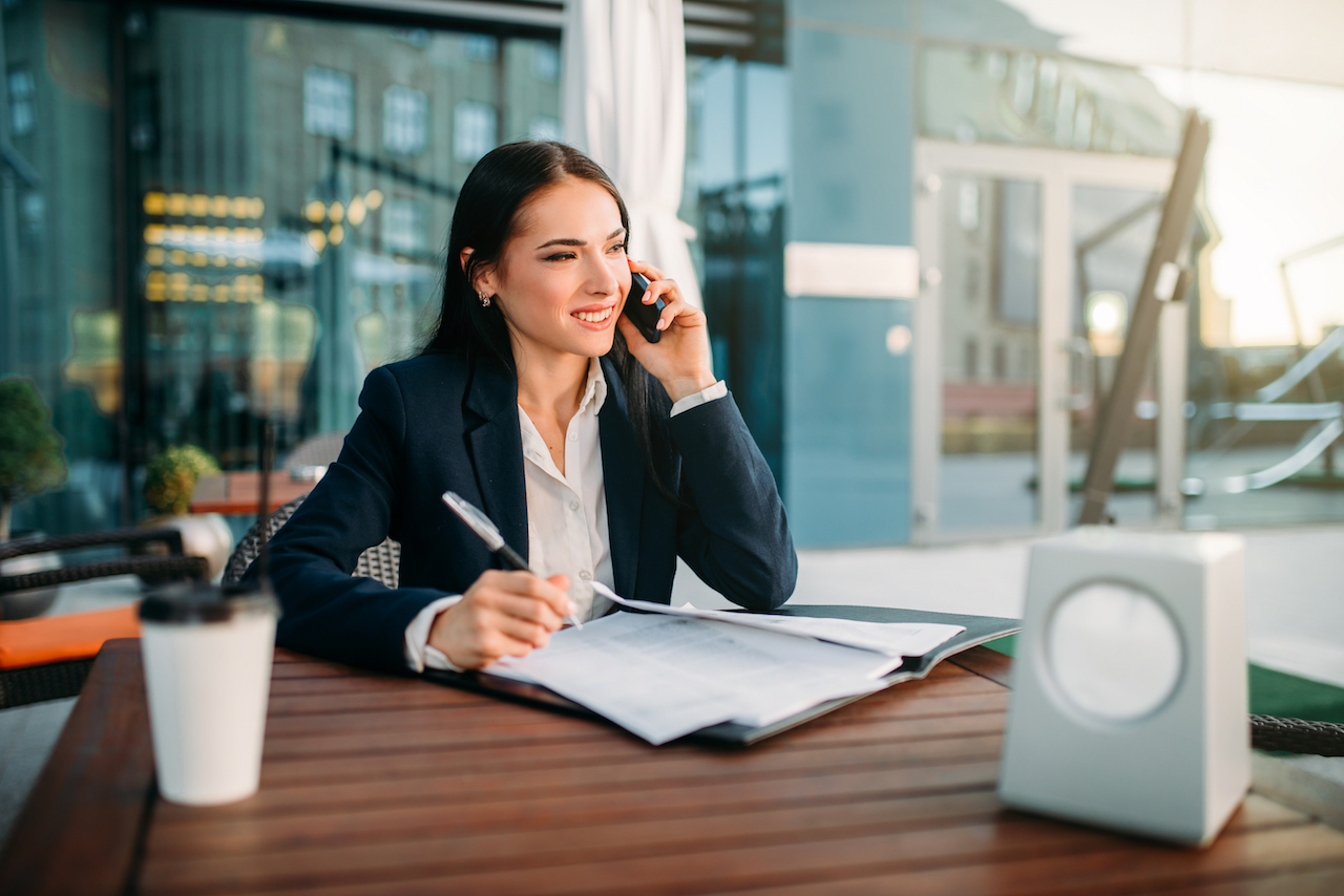 Business woman talks by mobile phone in cafe