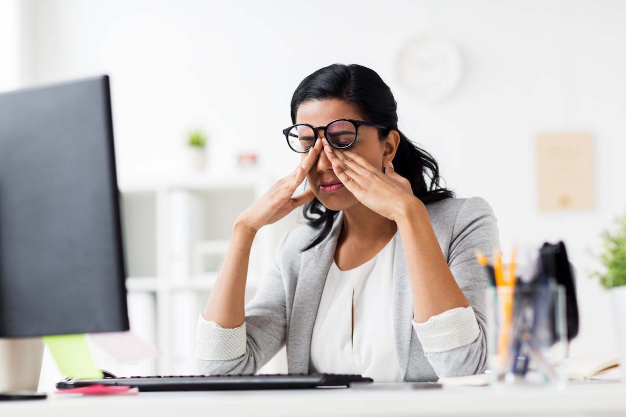 businesswoman rubbing tired eyes at office