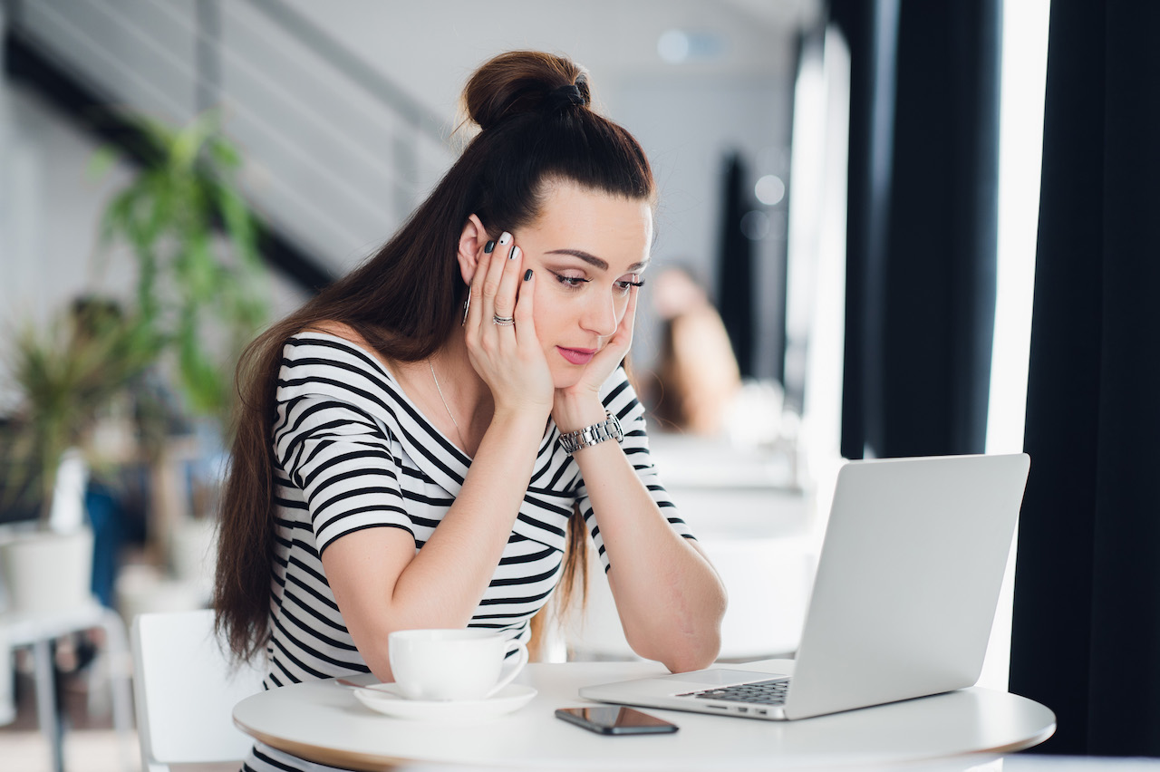 Disappointed businesswoman looking at business results on laptop screen in the office.